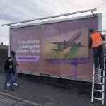 A billboard poster features a poster showing an aeroplane and the caption "stop adverts fuelling the climate crisis."